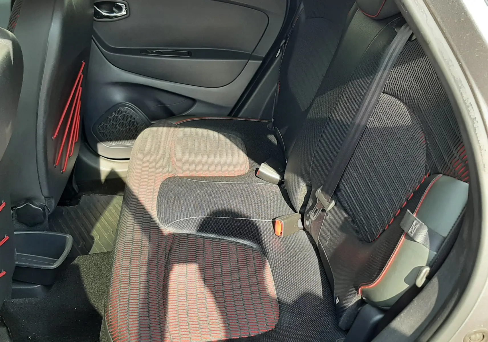 Vue intérieure côté droit des sièges arrière du Renault Captur gris Cassiopée, avec tissu noir et surpiqûres rouges.