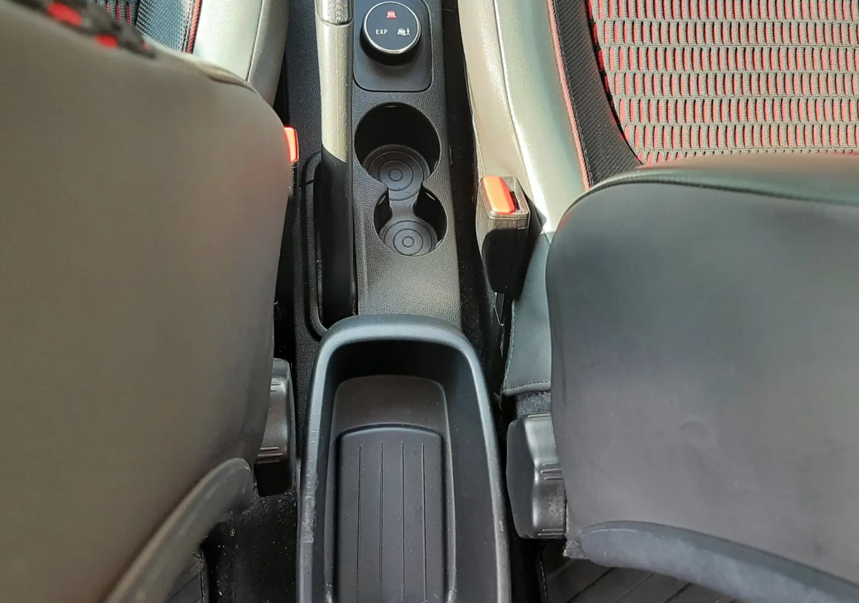 Vue plongeante sur la console centrale entre les sièges avant du Renault Captur gris cassiopée avec inserts rouges.