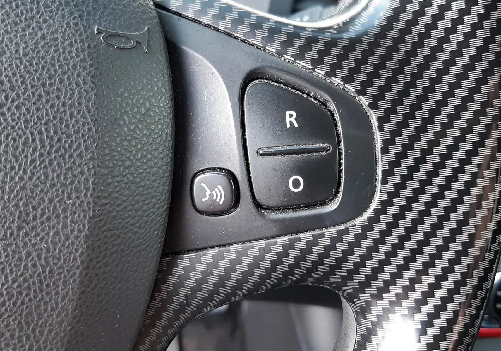 Gros plan sur les commandes du volant en plastique effet carbone du Renault Captur DCI 90CH INTENS 2016, intérieur noir.