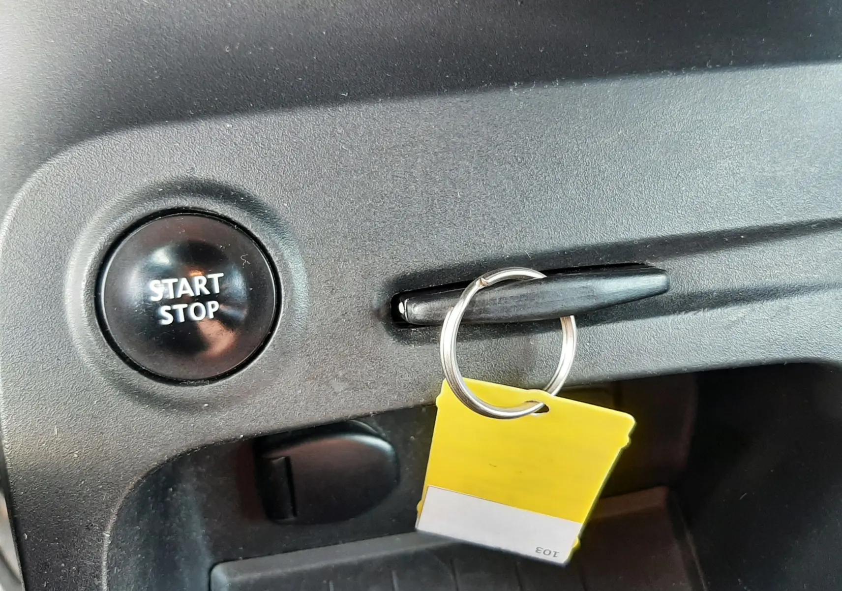 Gros plan sur le bouton Start/Stop et la clé avec porte-clés jaune dans l’habitacle du Renault Captur gris cassiopée toit noir.