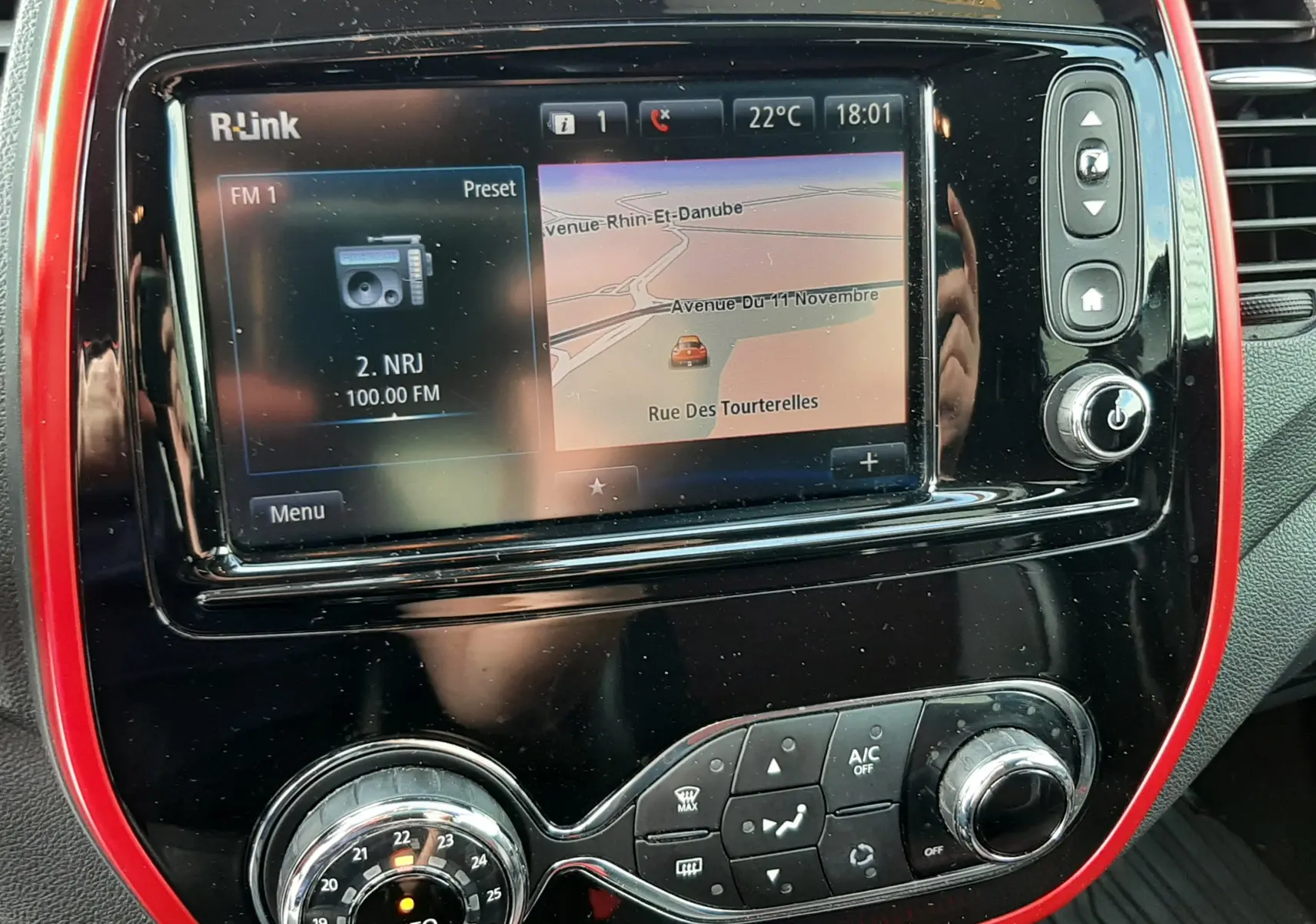 Vue rapprochée de la console centrale du Renault Captur 2016 avec écran R-Link et cadre rouge brillant autour.