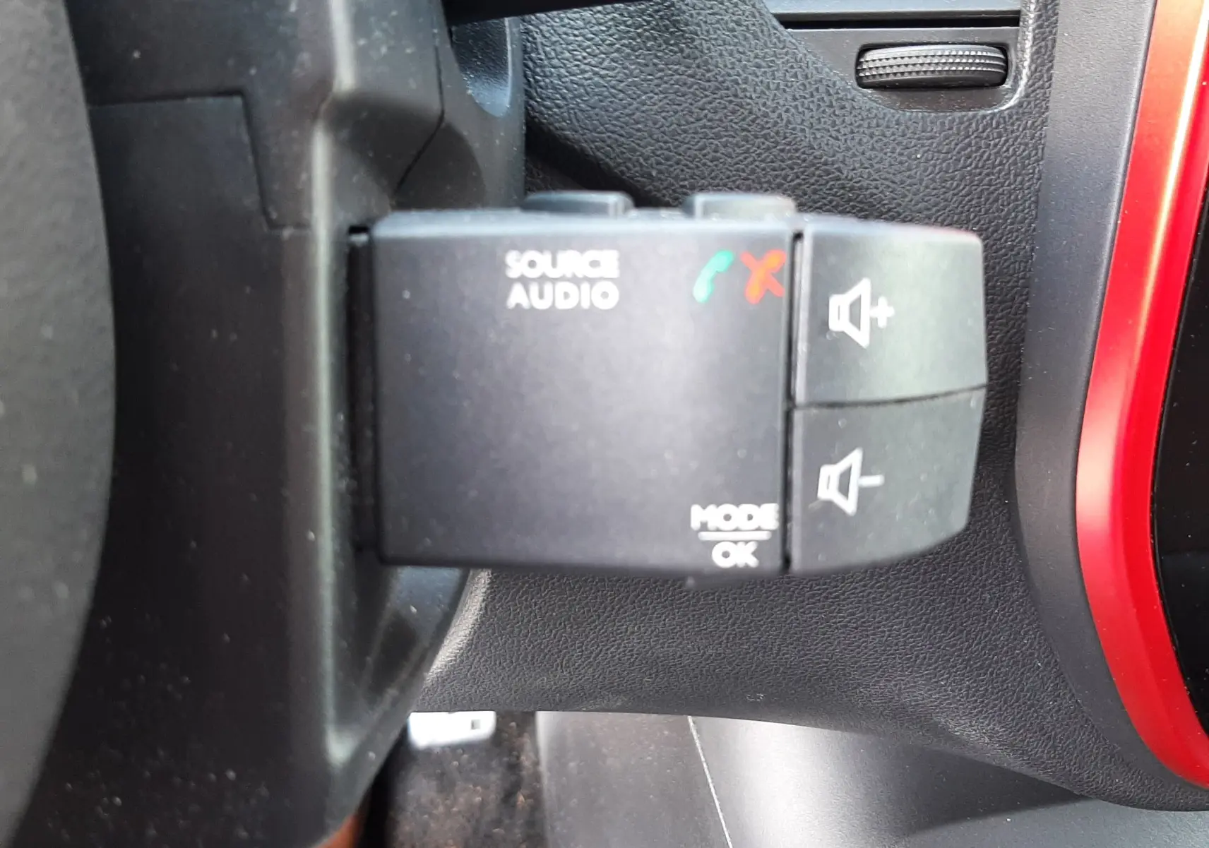 Gros plan sur la commande audio au volant d’un Renault Captur gris cassiopée avec intérieur noir, bouton start/stop visible.