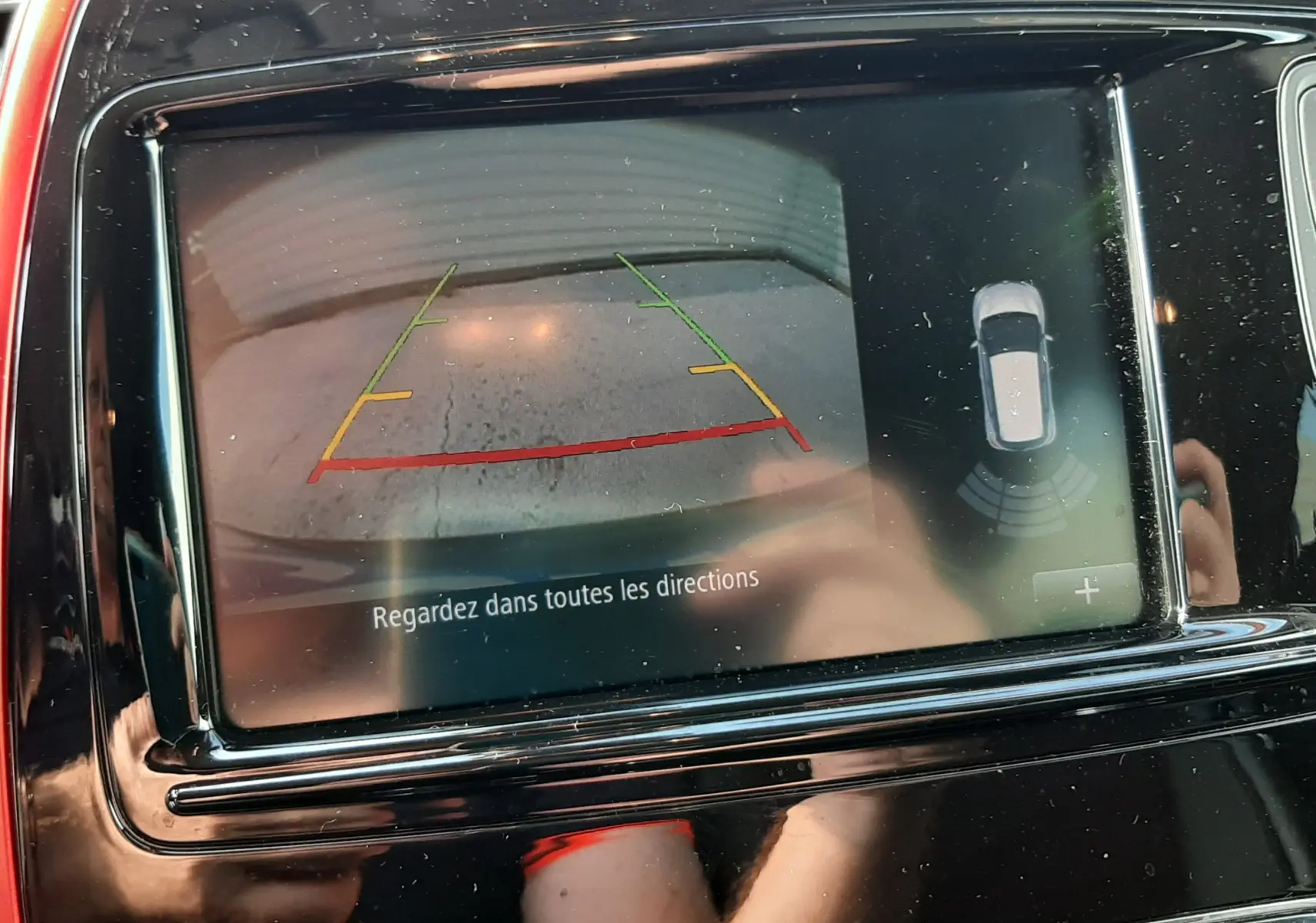 Écran central rouge et noir du Renault Captur montrant la caméra de recul avec guidage de trajectoire coloré.