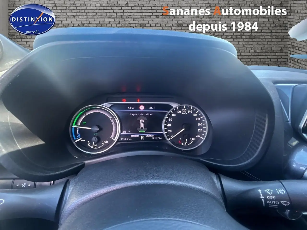 Vue rapprochée du tableau de bord du Nissan Juke blanc 2024, affichage numérique et compteurs analogiques visibles.