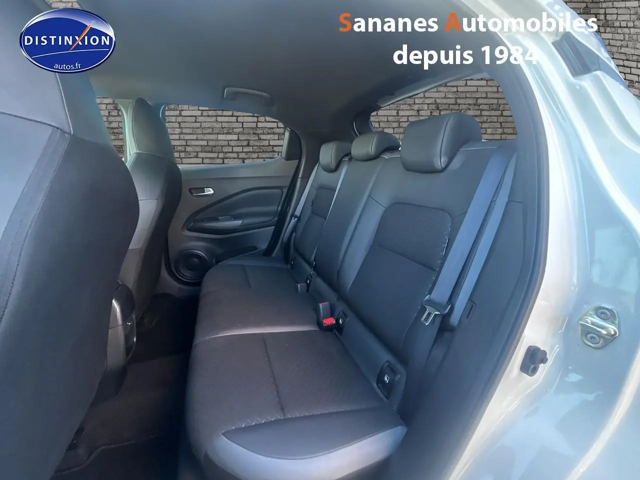 Vue côté droit de l’habitacle arrière du Nissan Juke blanc, montrant la banquette noire et la portière ouverte.
