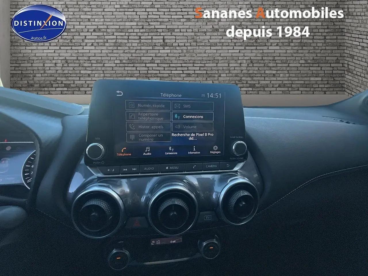 Vue intérieure du tableau de bord du Nissan Juke 2024 avec écran tactile central et commandes de climatisation circulaires.