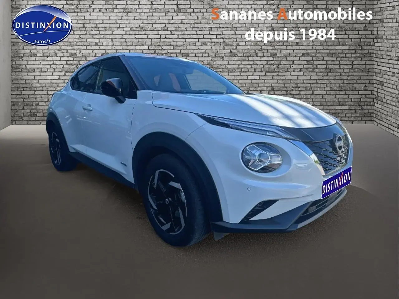 Nissan Juke blanc en 3/4 avant droit, avec coques de rétroviseurs noires et jantes au design moderne.