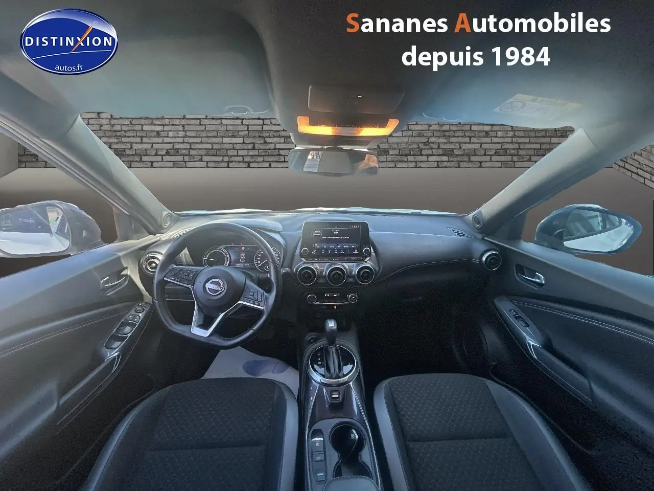 Vue intérieure avant du Nissan Juke 2024 blanc, avec tableau de bord moderne et écran tactile central.