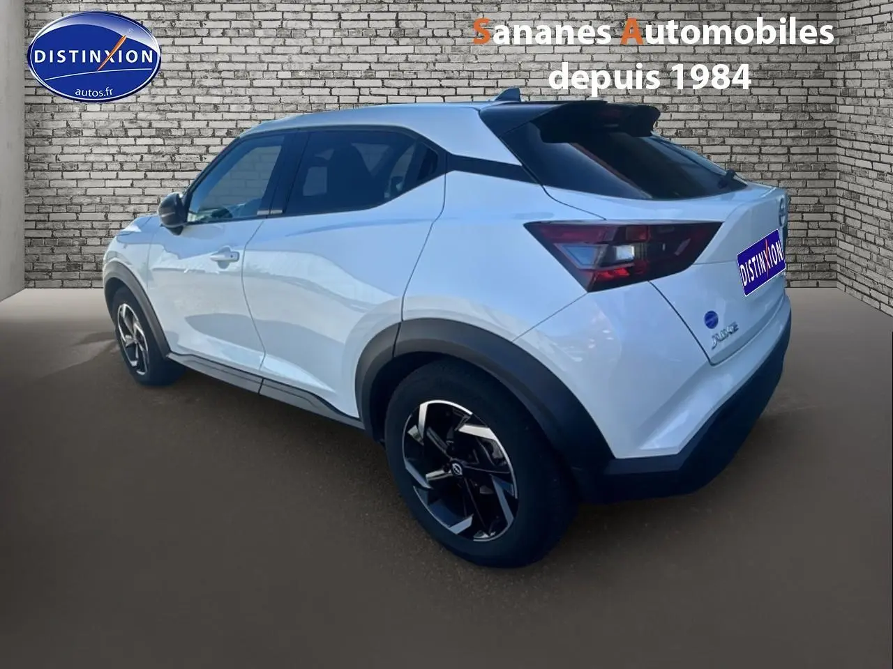 Vue 3/4 arrière droite du Nissan Juke blanc 2024 avec toit noir et jantes noires distinctives.