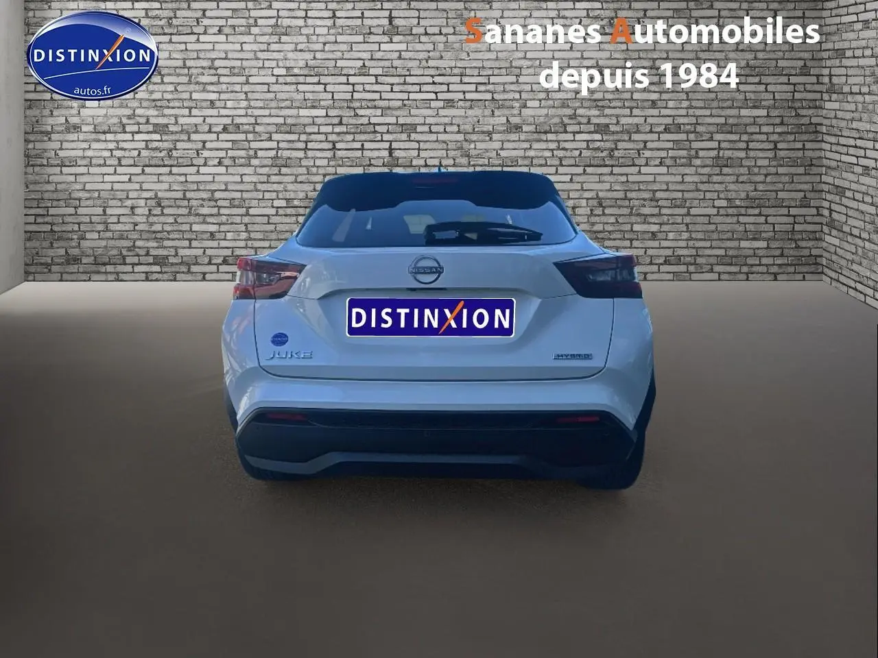 Vue arrière d'un Nissan Juke blanc 2024 hybride avec toit noir et feux arrière fumés dans un studio.