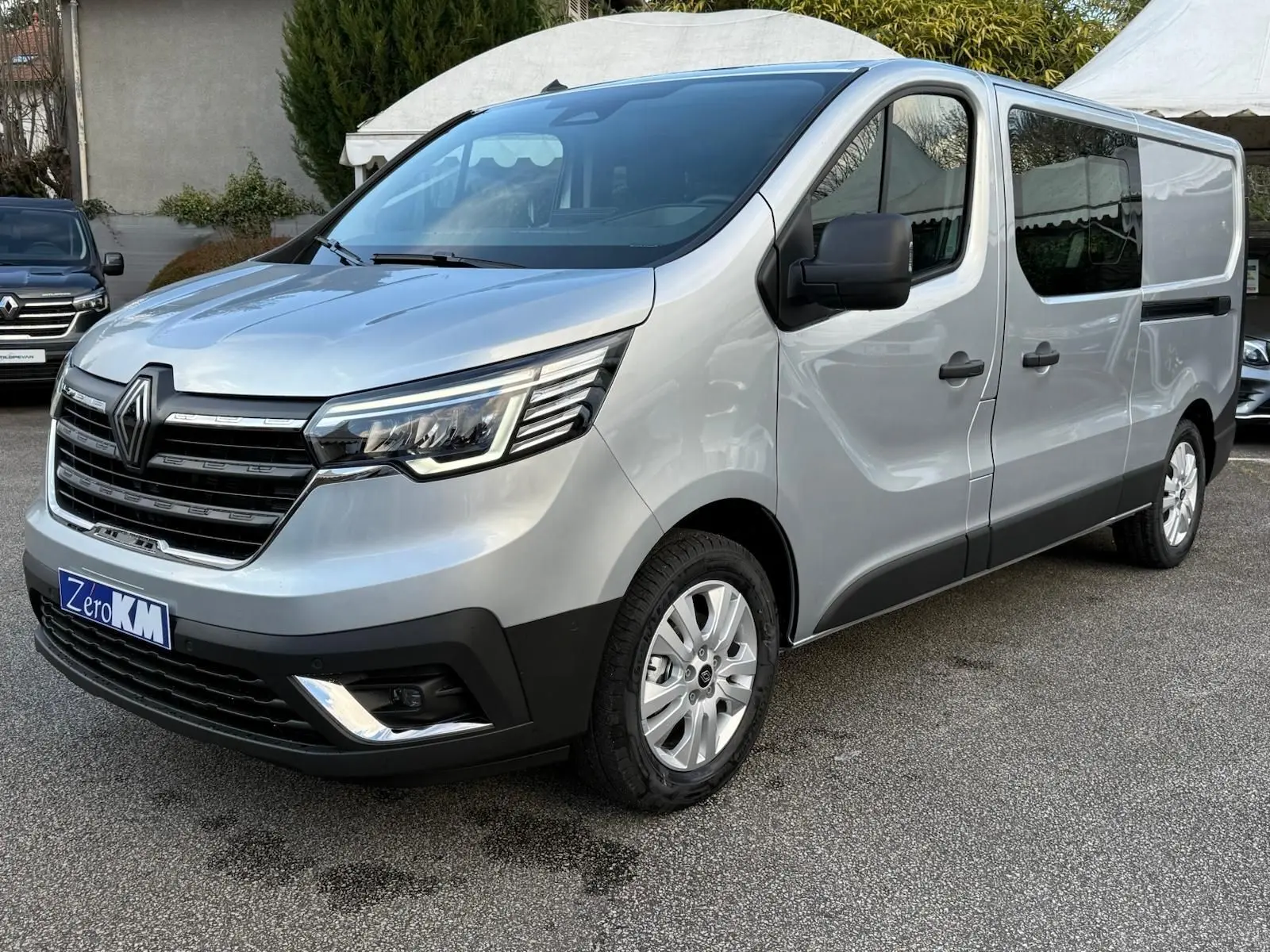 Vue 3/4 avant droit d'un Renault Trafic cabine approfondie gris Highland avec calandre noire et phares LED modernes.