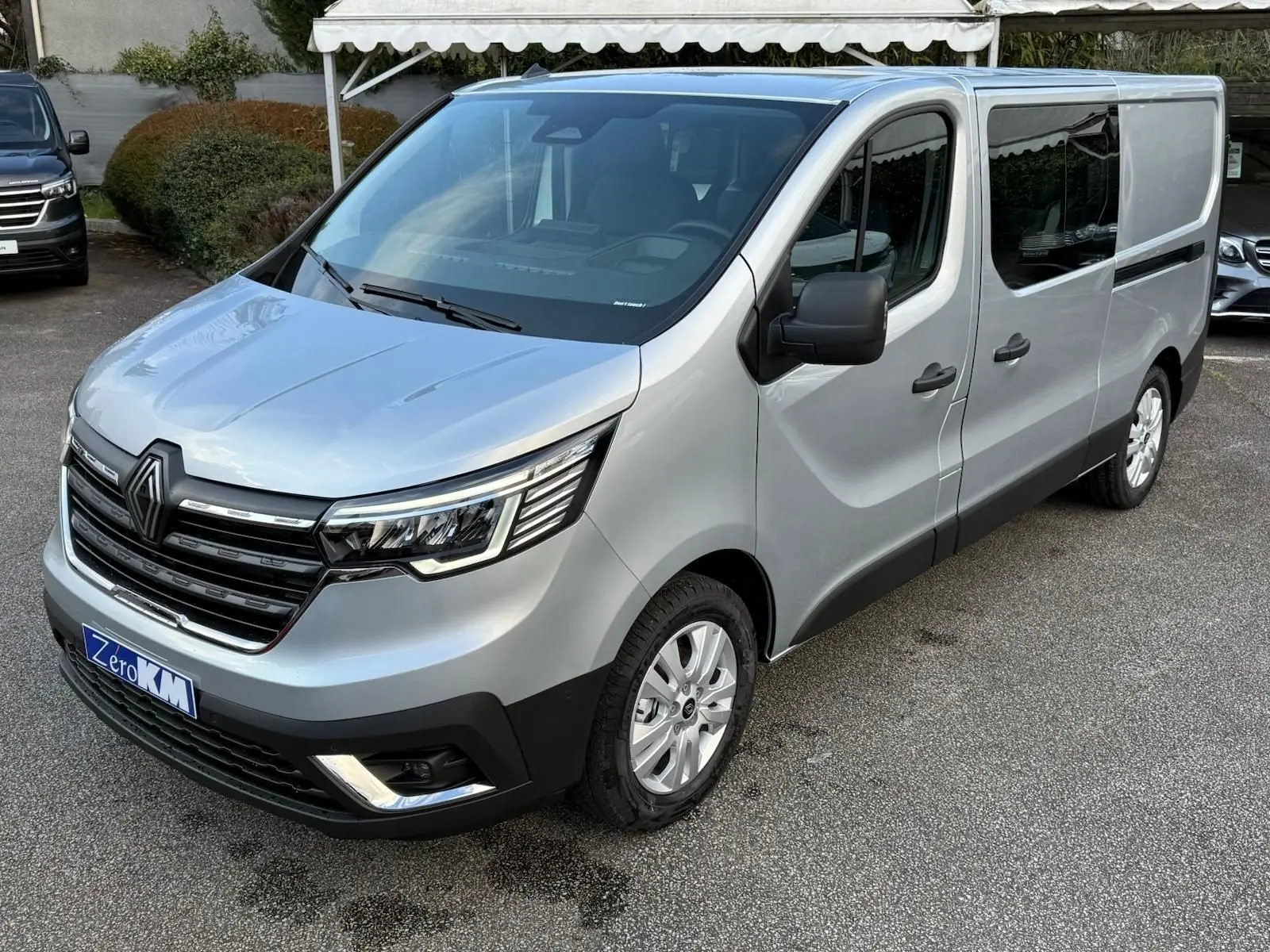 Vue intérieure côté conducteur du Renault Trafic cabine approfondie 2025, sièges gris et volant noir visibles.