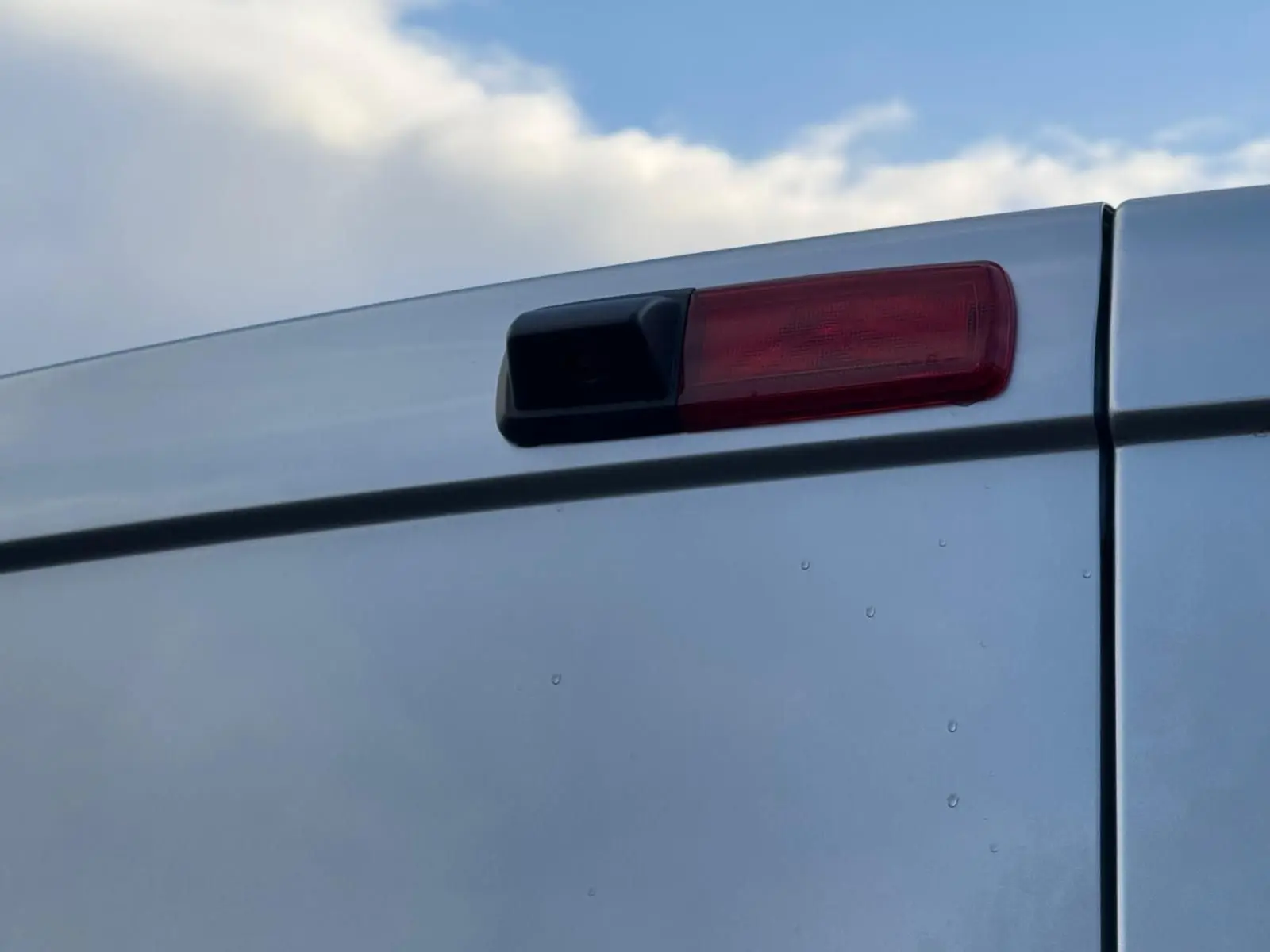 Vue 3/4 avant droit d'un Renault Trafic cabine approfondie gris Highland avec calandre noire et jantes argentées.