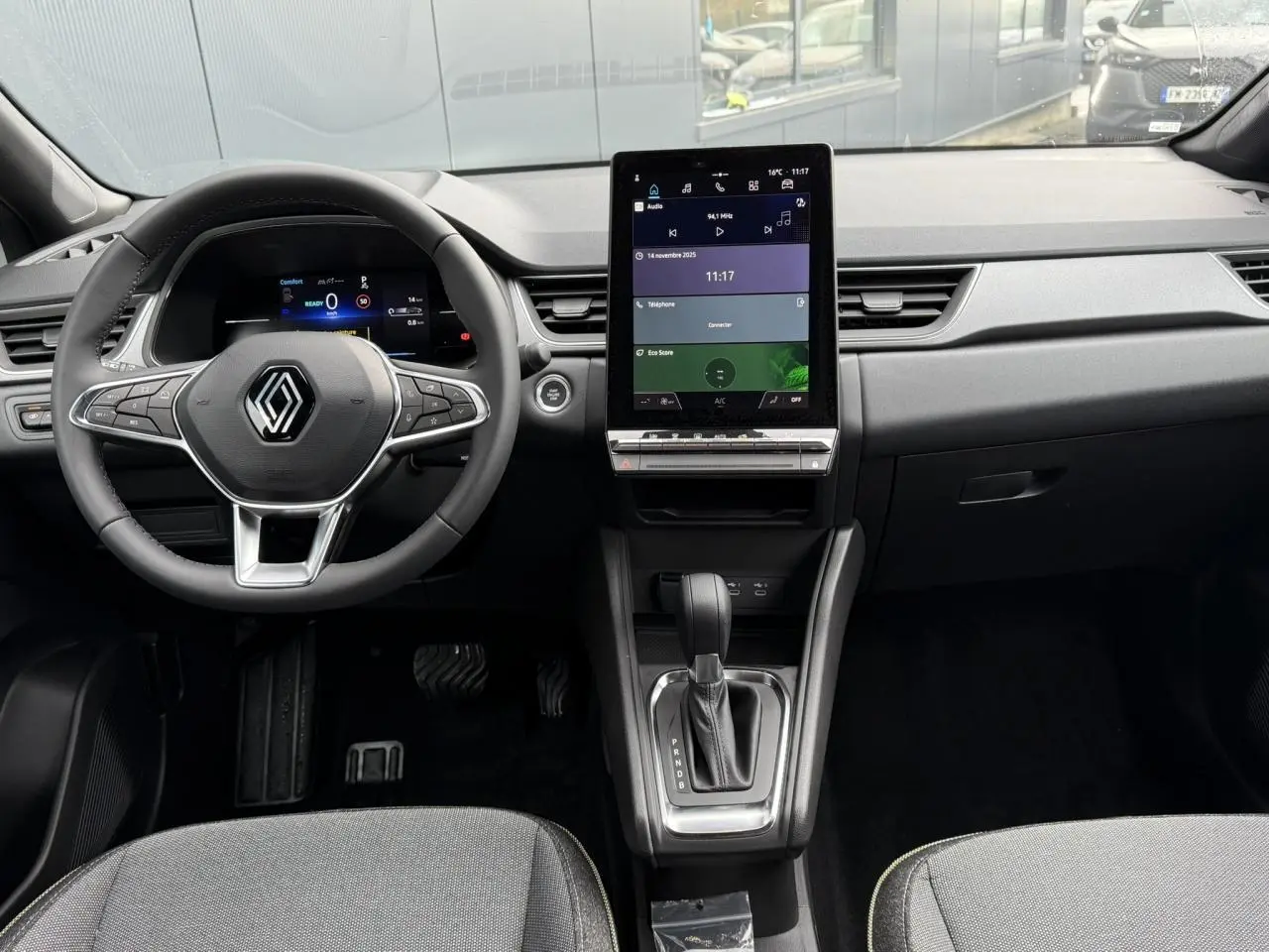 Vue intérieure frontale du tableau de bord du Renault Captur 2025 avec écran tactile vertical et volant multifonction.