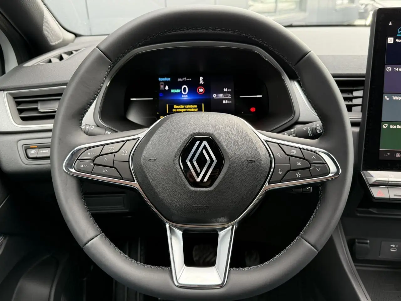 Gros plan sur le volant noir du Renault Captur 2025 avec tableau de bord numérique et écran tactile latéral visible.
