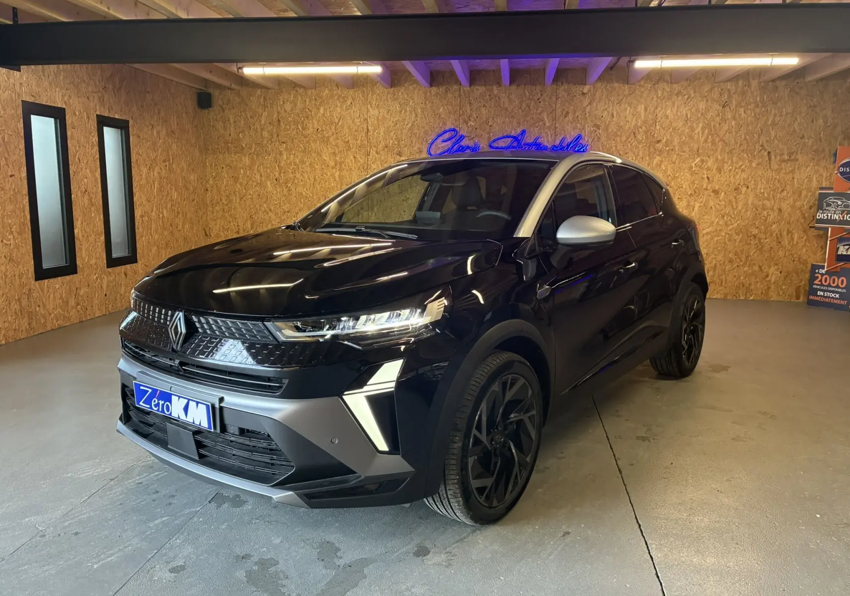 Renault Captur E-Tech hybride 2025 noir étoile avec toit gris, vue 3/4 avant en intérieur sous lumière artificielle.