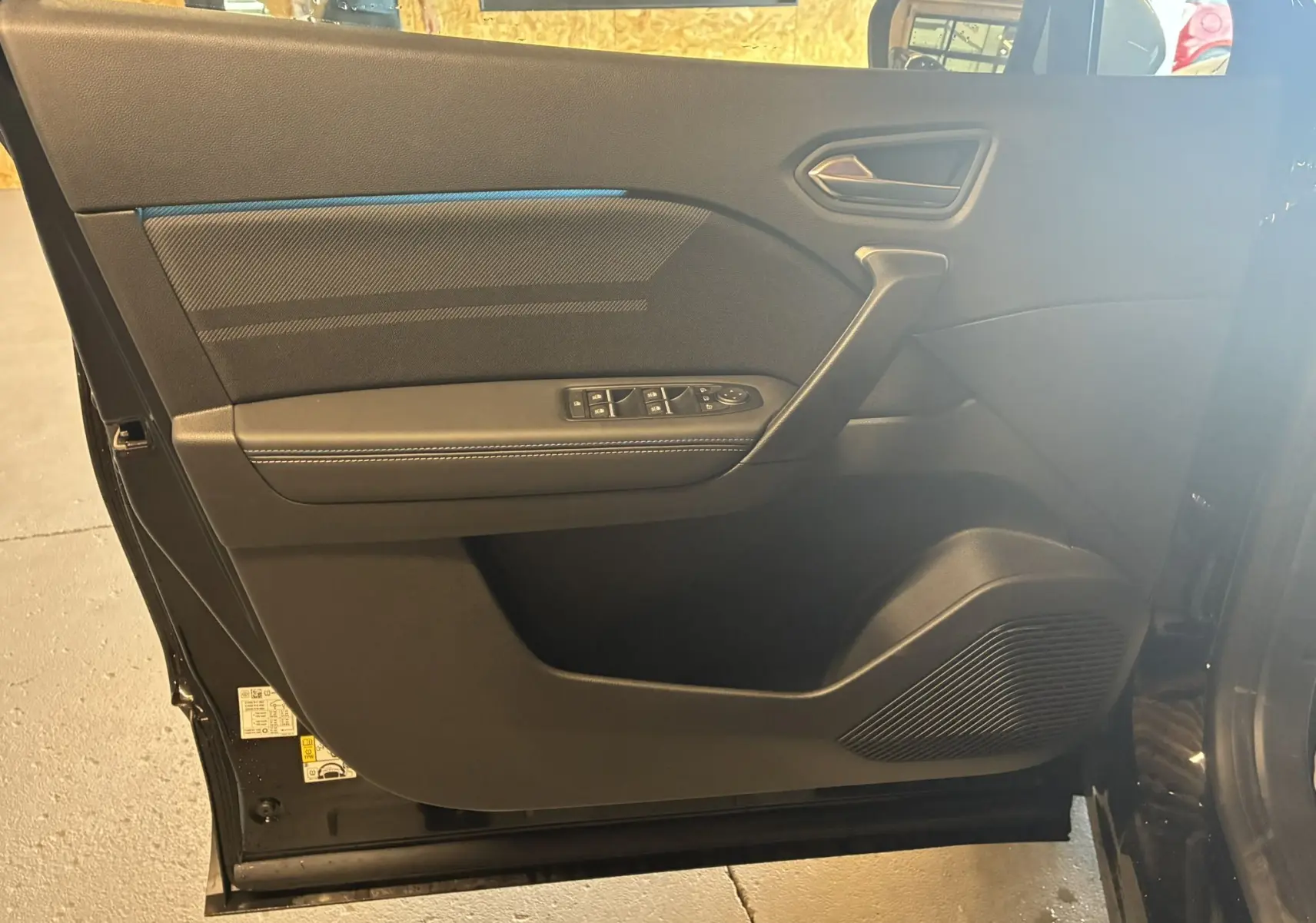 Porte intérieure côté gauche du Renault Captur E-Tech hybride 2025 en noir étoile métal avec surpiqûres blanches.