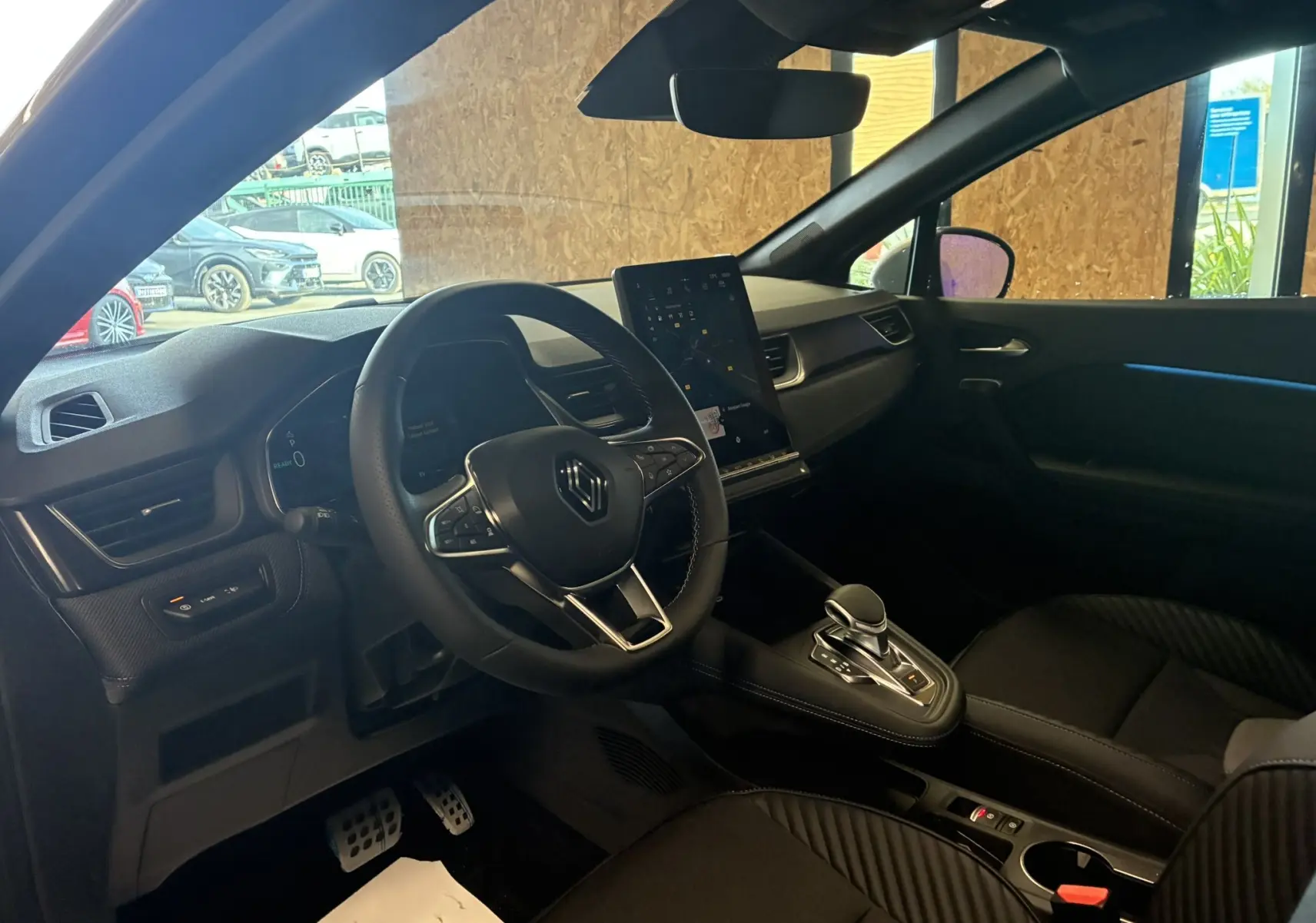 Intérieur noir du Renault Captur E-Tech 2025 vu côté conducteur, avec volant multifonction et écran tactile vertical.