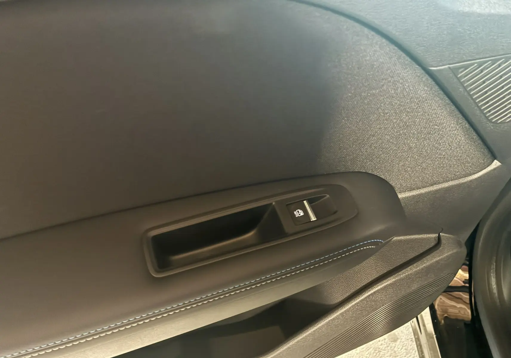 Gros plan sur la poignée intérieure et le bouton de verrouillage de la porte côté droit du Renault Captur noir étoile métal 2025.
