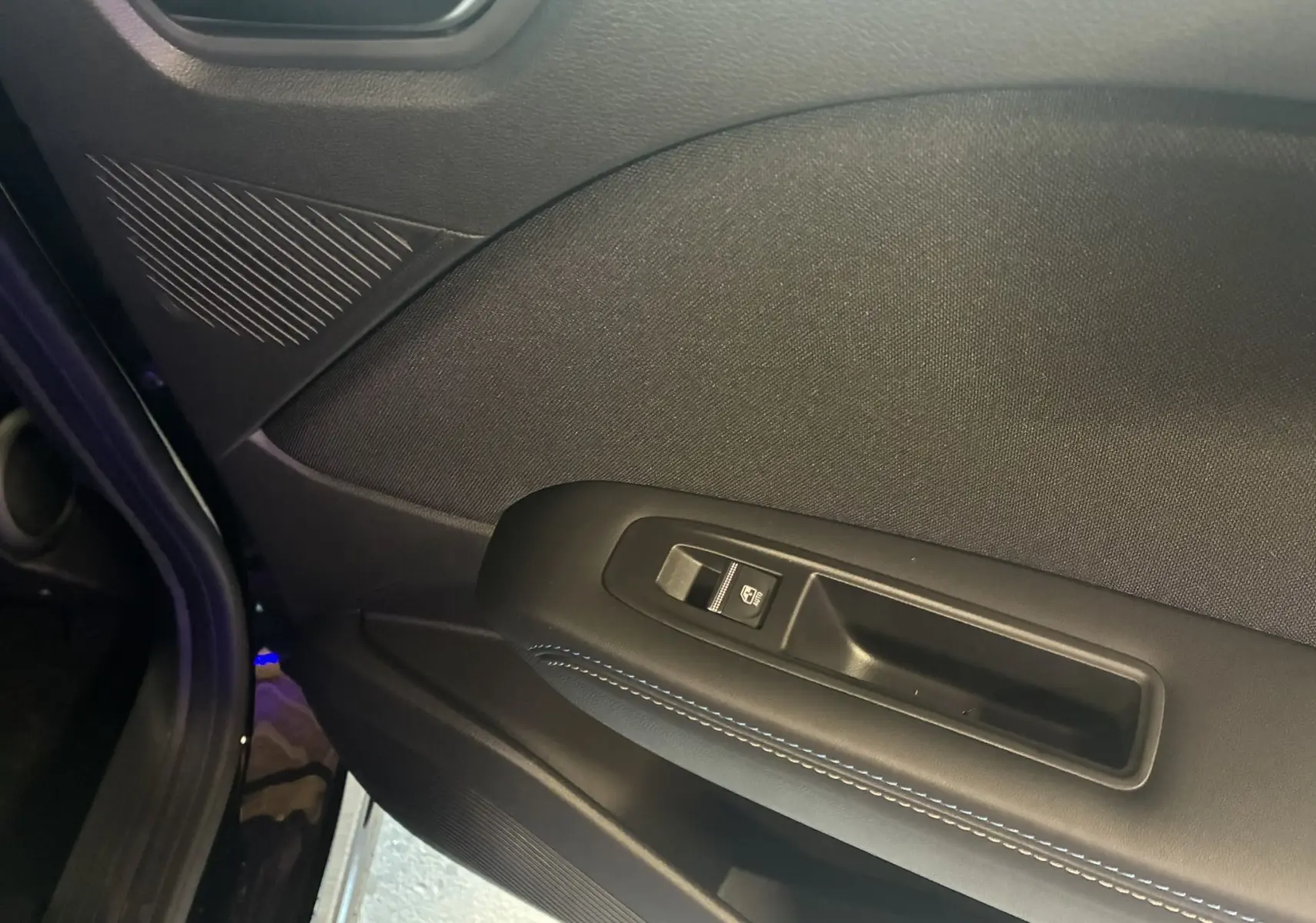 Gros plan sur la porte intérieure côté gauche du Renault Captur E-Tech noir étoile avec bouton de commande de vitre et surpiqûres bleues.