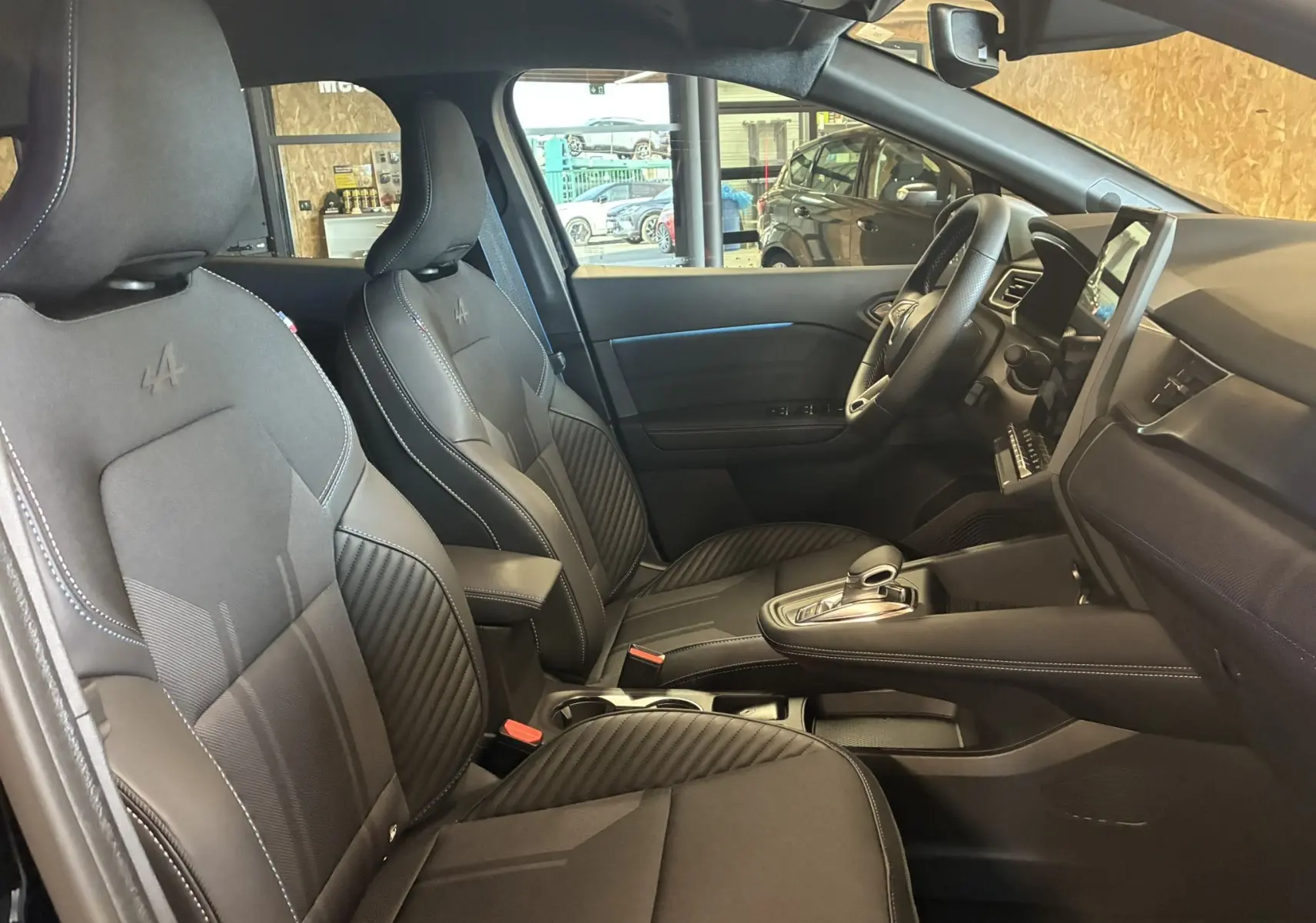 Vue intérieure côté conducteur du Renault Captur E-Tech Full Hybrid 2025, sièges noirs avec logo Alpine et console centrale moderne.