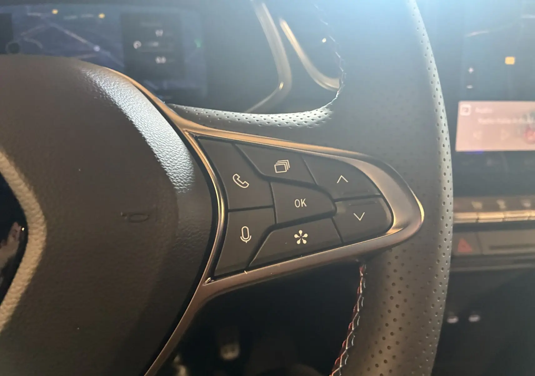 Gros plan sur les commandes multifonctions à droite du volant en cuir perforé du Renault Captur hybride 2025.