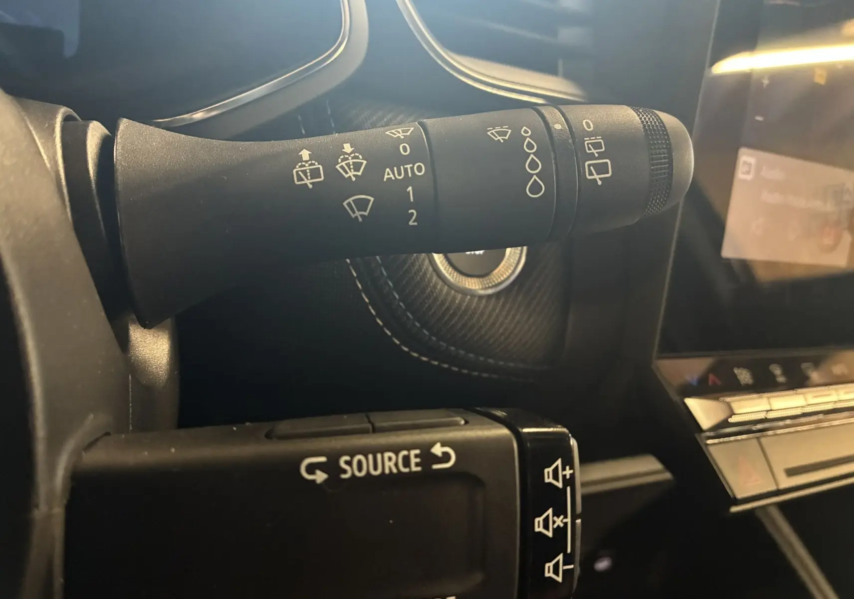 Gros plan sur la commande des essuie-glaces et du régulateur audio dans l'habitacle noir du Renault Captur E-Tech 2025.
