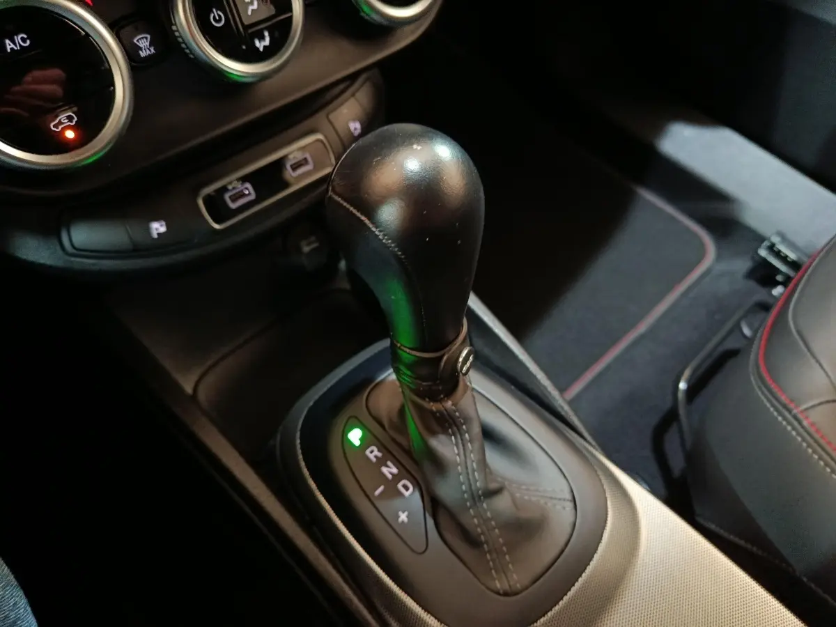 Gros plan sur le levier de vitesse automatique noir de la FIAT 500X 2021, avec coutures apparentes et console environnante.