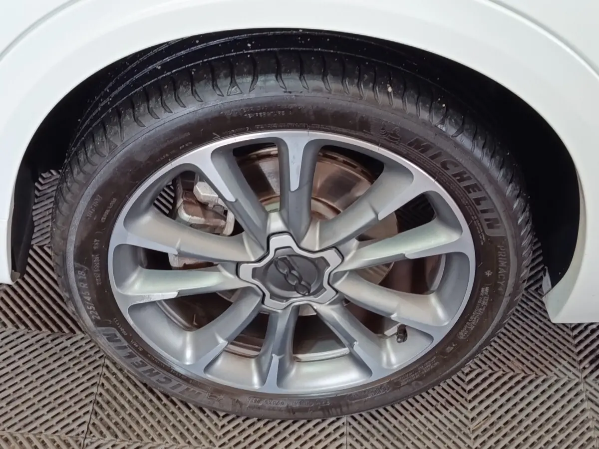Gros plan sur la jante alliage argentée avec logo FIAT au centre d’une roue de FIAT 500X blanche.