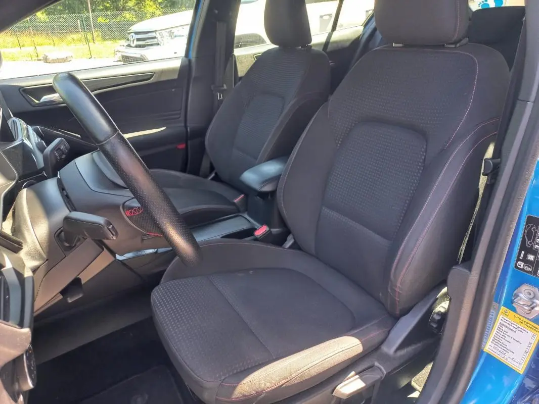 Intérieur de la Ford Focus 2019 bleu, vue côté conducteur montrant sièges noirs avec surpiqûres rouges et volant cuir.