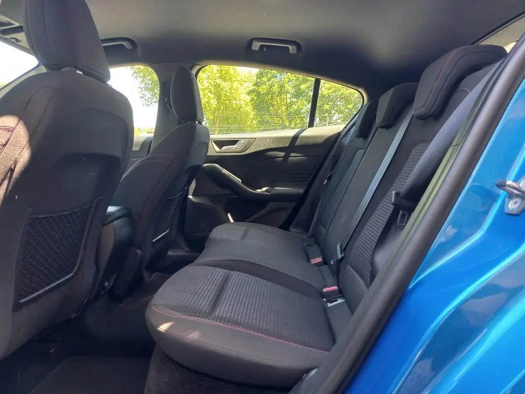 Vue intérieure arrière côté droit de la Ford Focus 2019 bleue, montrant les sièges arrière en tissu noir avec surpiqûres rouges.