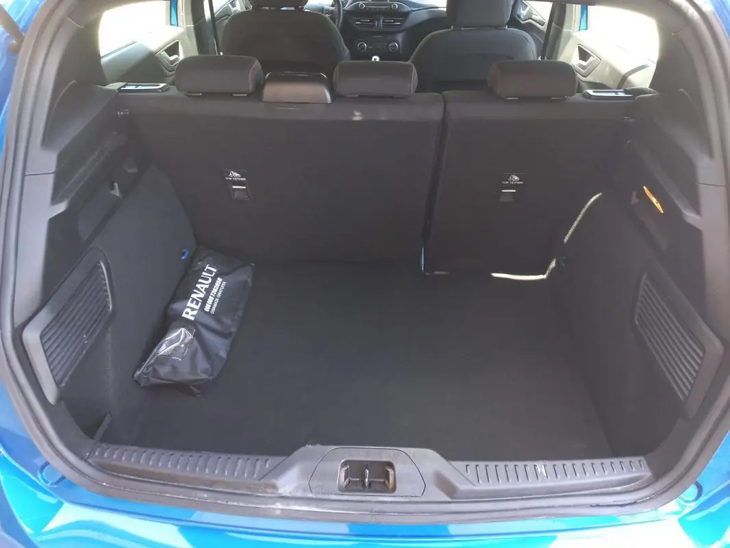 Coffre ouvert vu de l'arrière d'une Ford Focus bleu 2019, avec banquette arrière et sac Renault noir à l'intérieur.