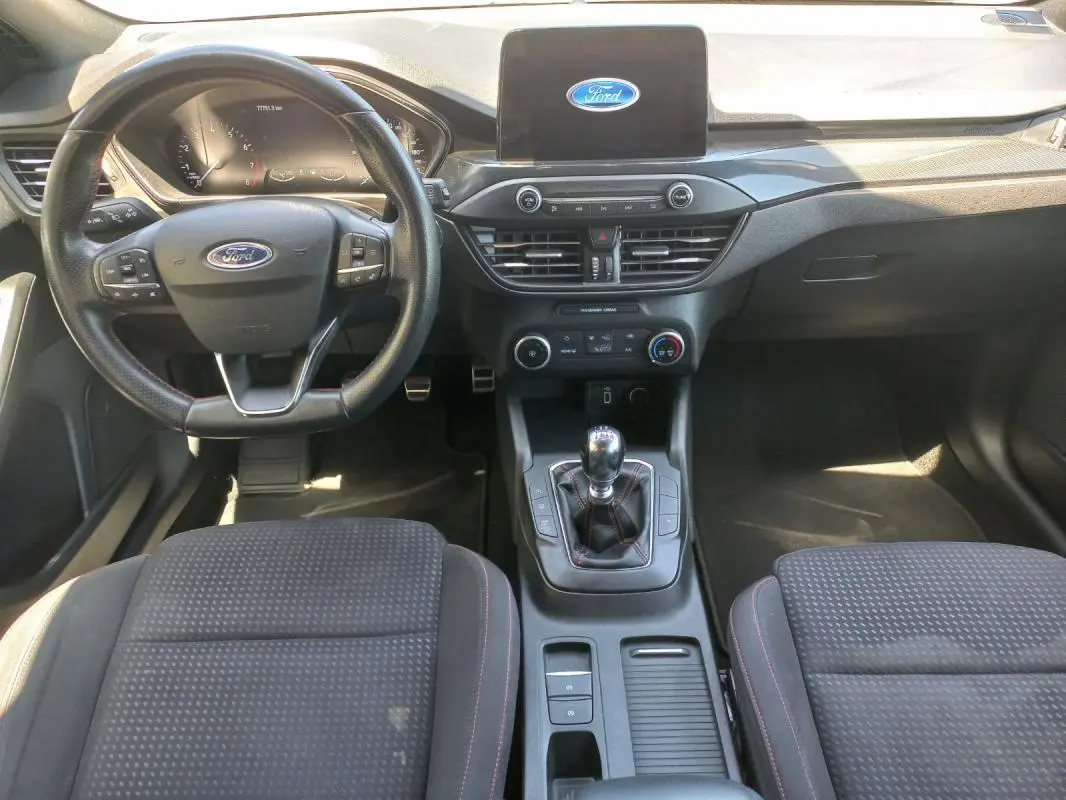 Vue intérieure avant de la Ford Focus 2019 bleu, avec volant multifonctions, écran central et levier de vitesse manuel.