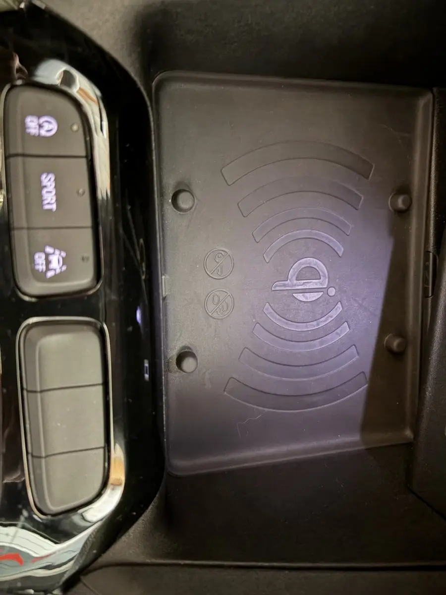 Vue rapprochée de la console centrale de l’Opel Corsa 2025, avec zone de recharge sans fil et boutons de contrôle sport et assistance.