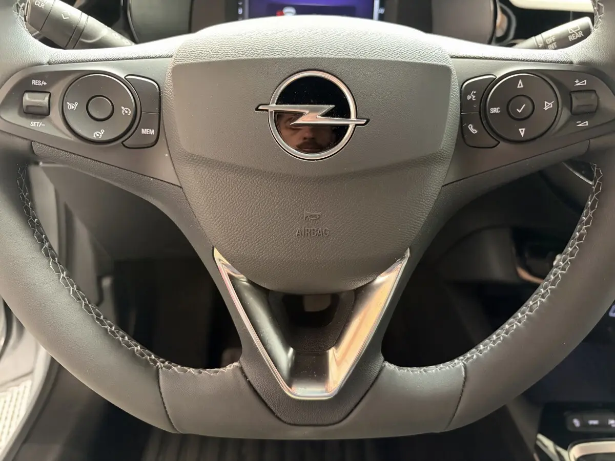 Gros plan sur le volant cuir synthétique noir de l'Opel Corsa 2025 avec commandes multifonctions intégrées.