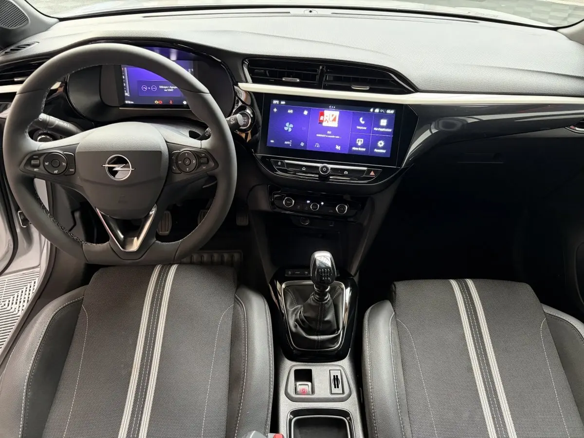 Vue intérieure avant de l’Opel Corsa gris clair 2025, volant multifonctions cuir, écran tactile central et boîte manuelle.