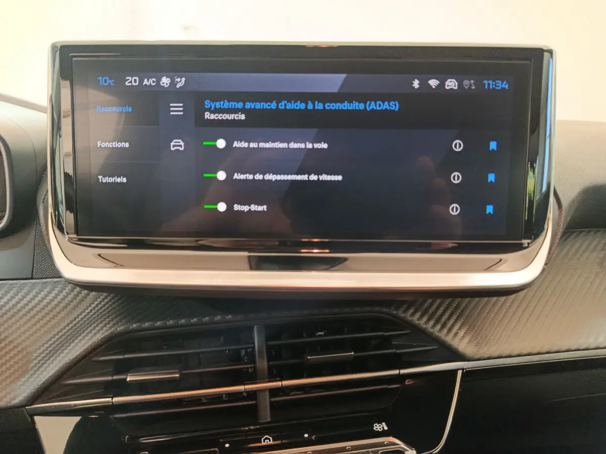 Vue rapprochée de l'écran tactile central de la Peugeot 208 PureTech 100 S&S Allure 2025 avec affichage des aides à la conduite.