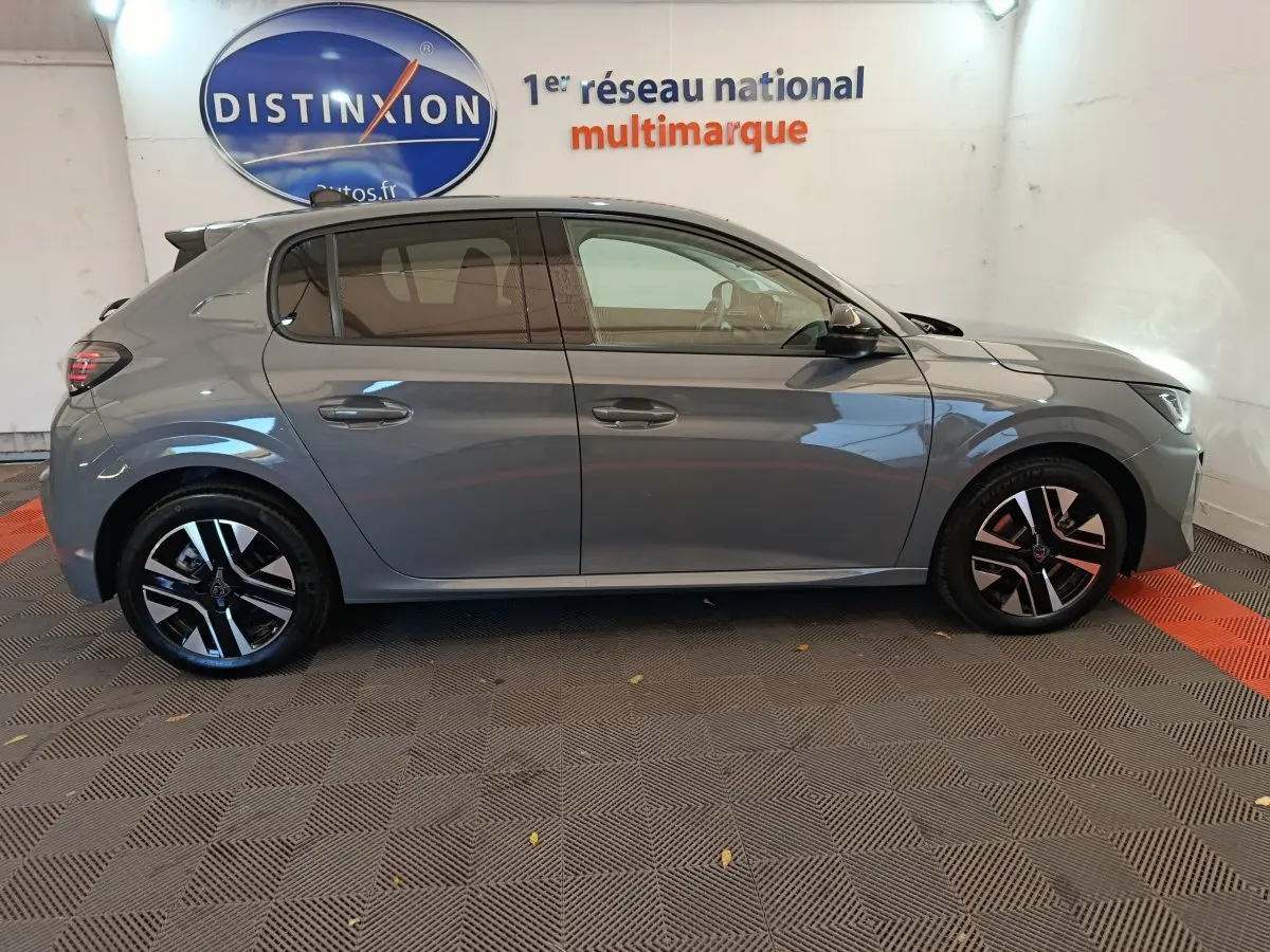 Profil latéral droit d'une Peugeot 208 gris foncé 2025 avec jantes noires et détails modernes en concession.