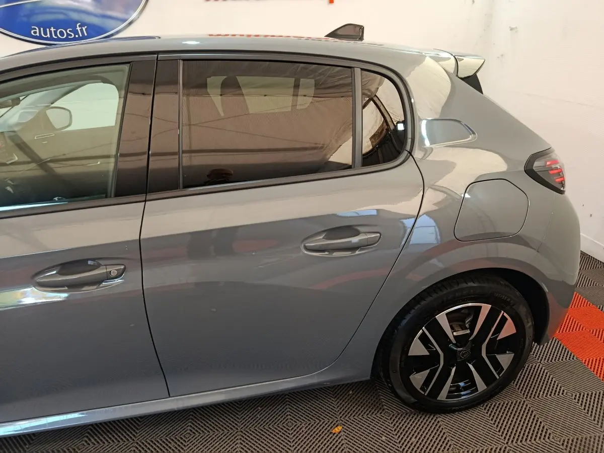 Vue latérale droite d'une Peugeot 208 gris foncé, mettant en valeur les poignées de porte et la jante au design moderne.