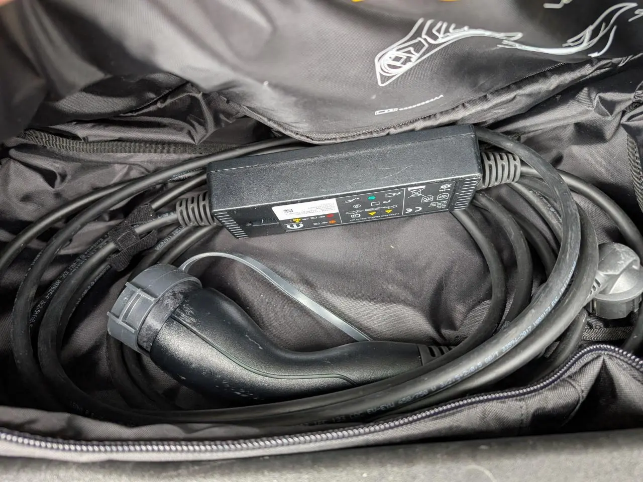 Gros plan sur le câble de recharge noir rangé dans un sac, accessoire du Jeep Wrangler 2024 hybride noir.