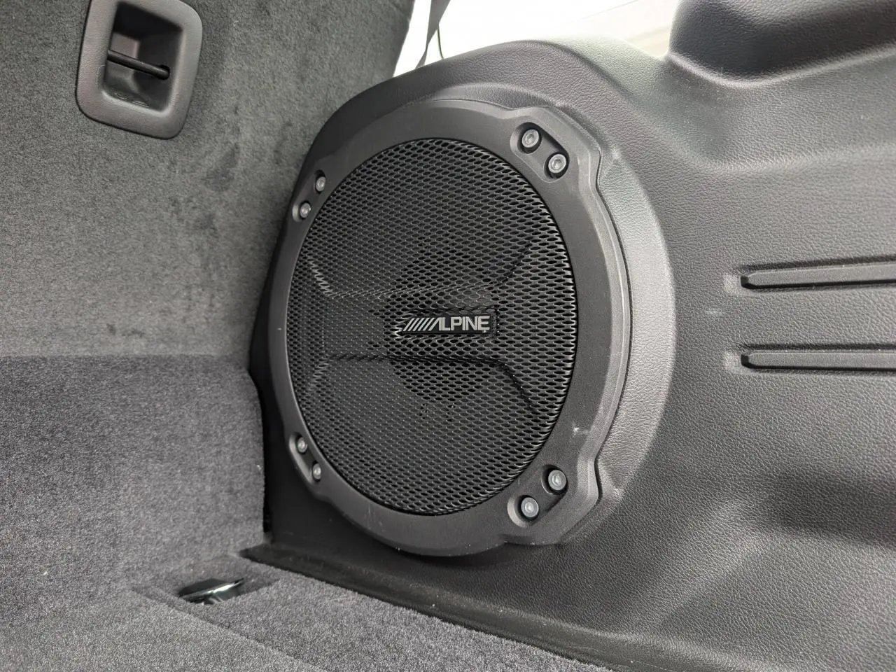 Gros plan sur le haut-parleur Alpine noir intégré dans le coffre du Jeep Wrangler 2024 Unlimited Sahara.