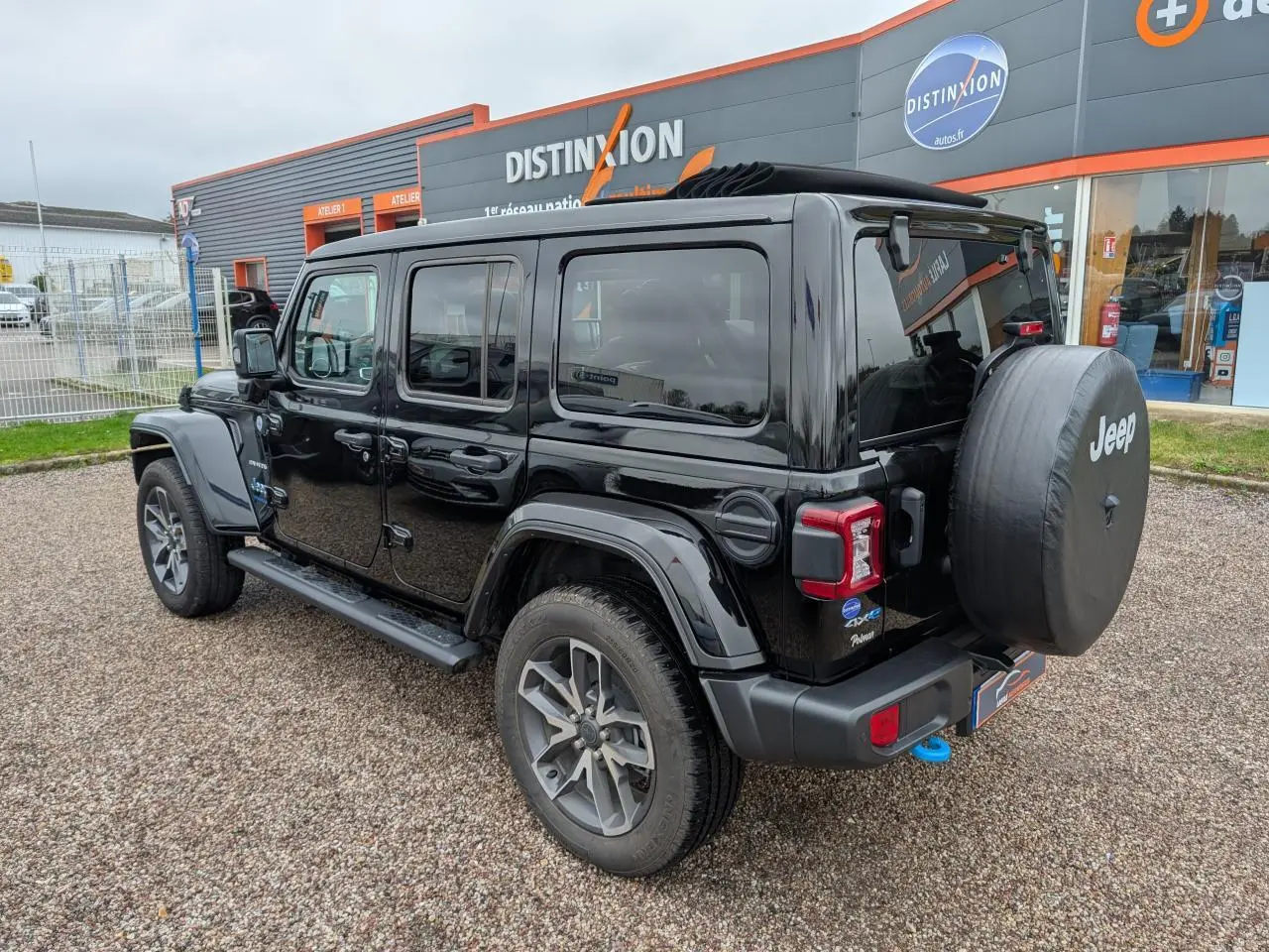 Jeep Wrangler 2024 noir vue 3/4 arrière droit avec roue de secours et marchepied visible.