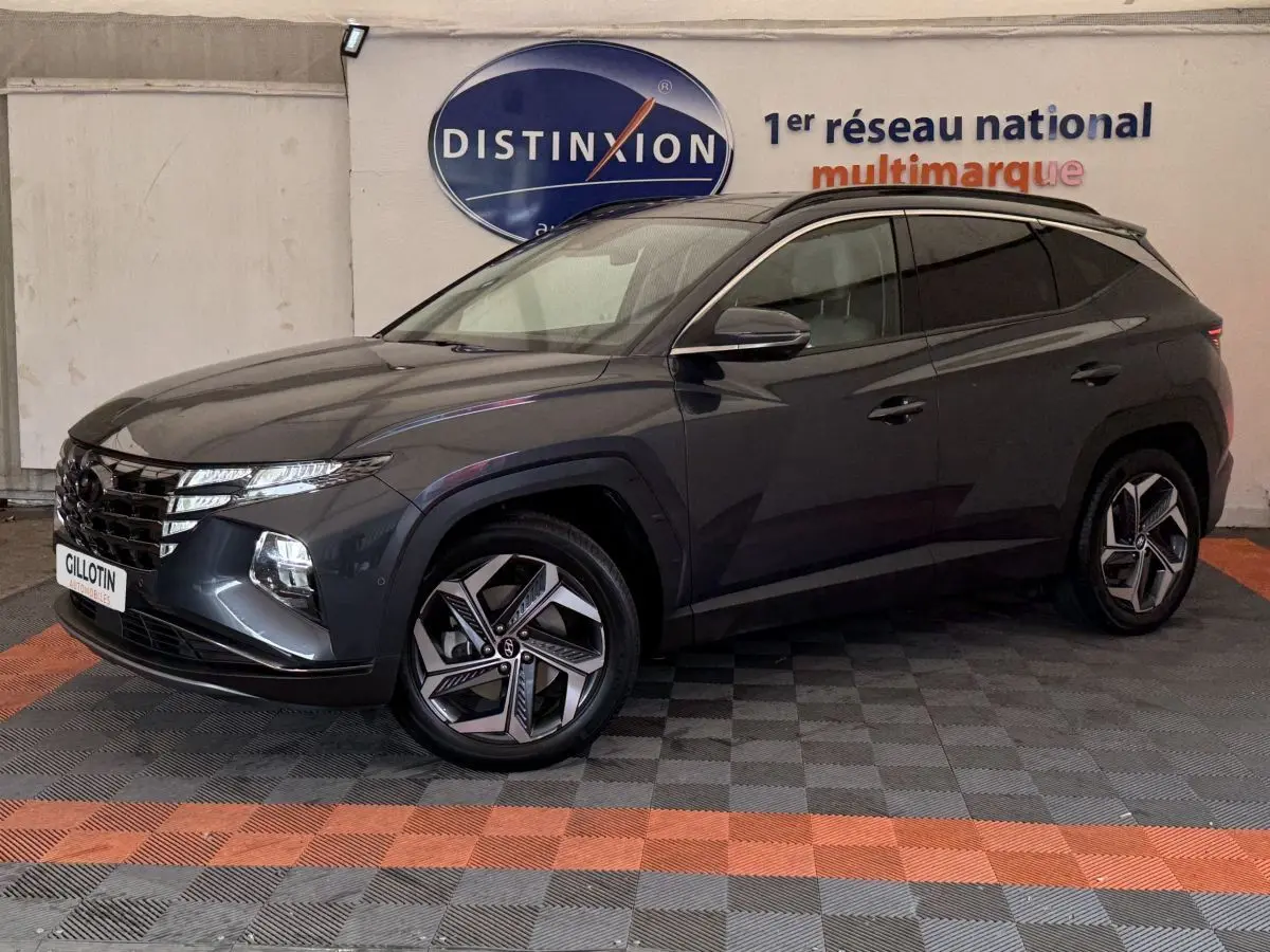 Vue 3/4 avant gauche d'un Hyundai Tucson gris foncé avec jantes au design moderne, stationné en intérieur showroom.