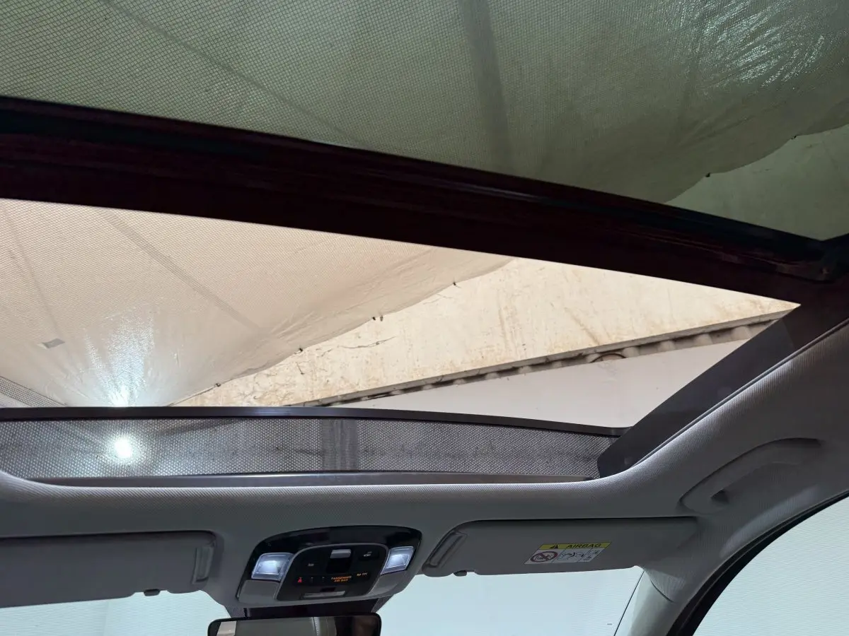 Vue intérieure du toit ouvrant en verre inclinable du Hyundai Tucson gris foncé, avec pare-soleil partiellement déployé.
