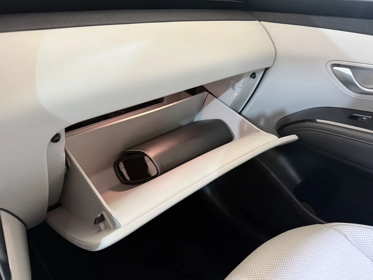 Vue intérieure côté passager du Hyundai Tucson 1.6 Hybrid 230 Executive 2021, boîte à gants ouverte avec pochette noire.