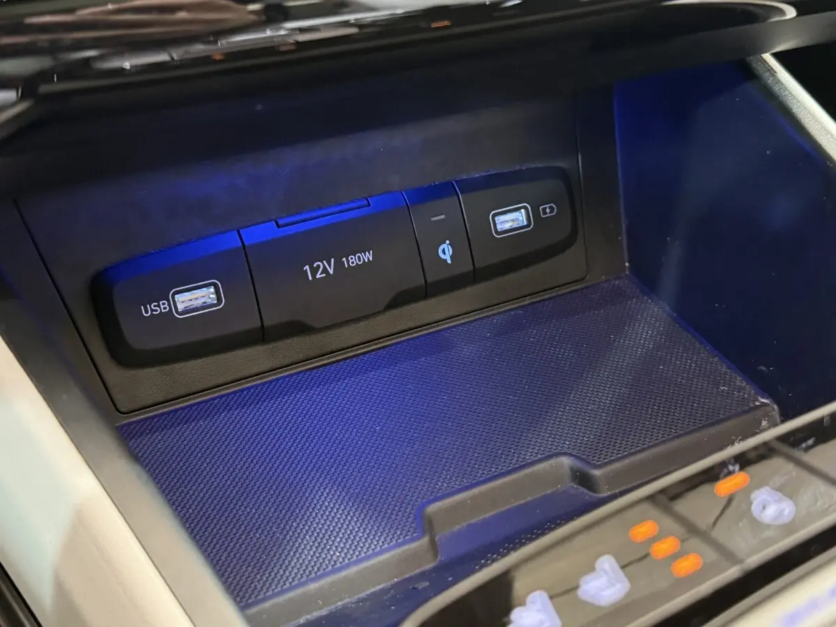 Gros plan sur la zone de recharge à induction avec ports USB et prise 12V du Hyundai Tucson gris foncé 2021.