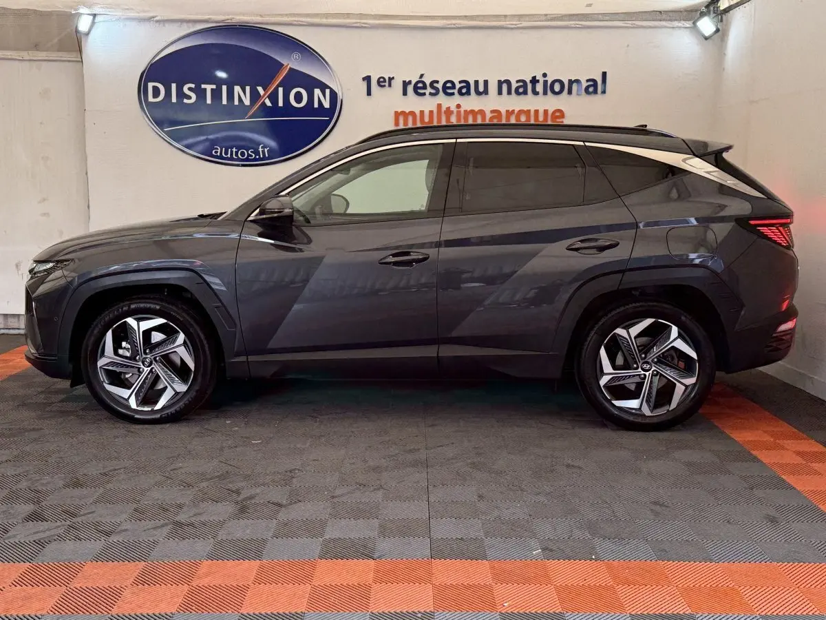 Vue latérale droite du Hyundai Tucson gris foncé 2021 avec jantes alliage et vitres teintées en intérieur showroom.