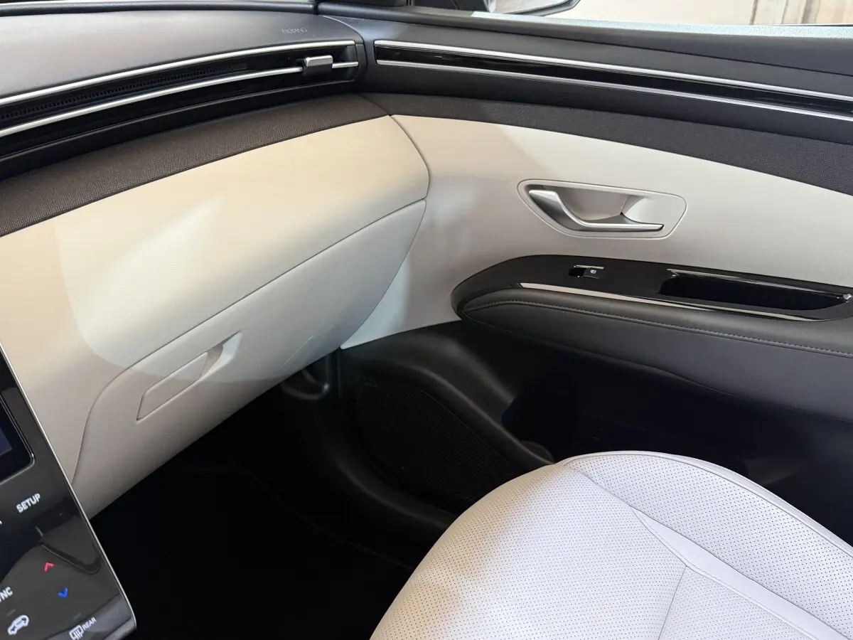 Vue intérieure côté passager avant du Hyundai Tucson 1.6 Hybrid 230 Executive, avec sellerie claire et garnitures bicolores.