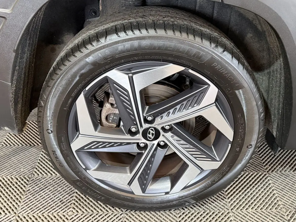 Gros plan sur la roue avant droite du Hyundai Tucson gris foncé, mettant en valeur la jante alliage au design moderne.