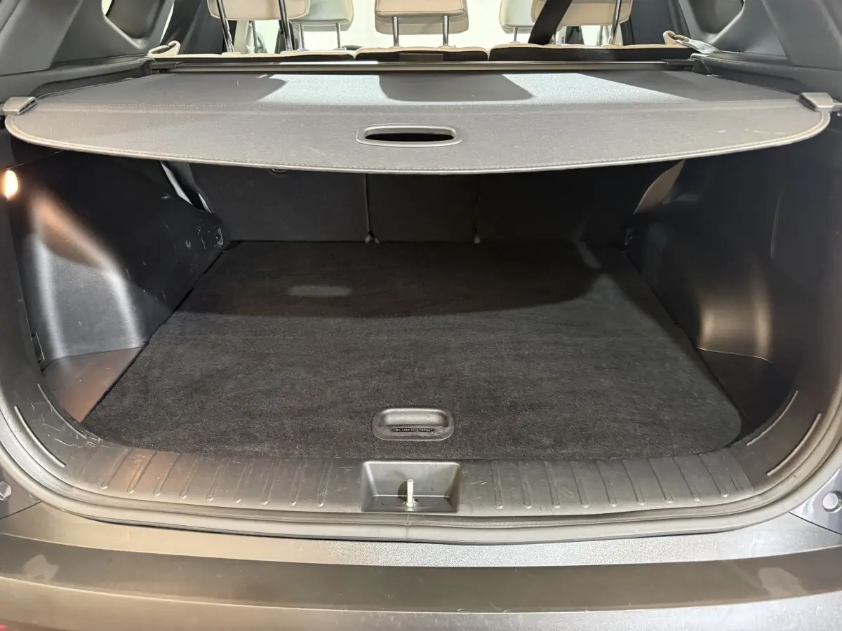 Coffre ouvert vu de l'arrière d'un Hyundai Tucson gris foncé avec cache-bagages et sièges arrière beiges.